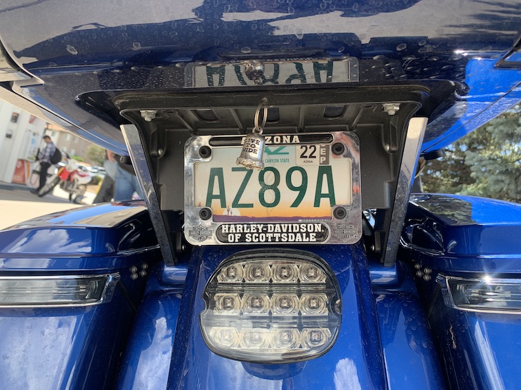 The rear end of a blue motorcycle with a fender, brake light, luggage packs, and a license plate that says AZ89A