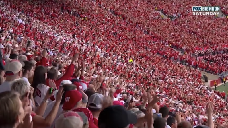 Thousands of football fans, mostly dressed in red and white, celebrating in the stands
