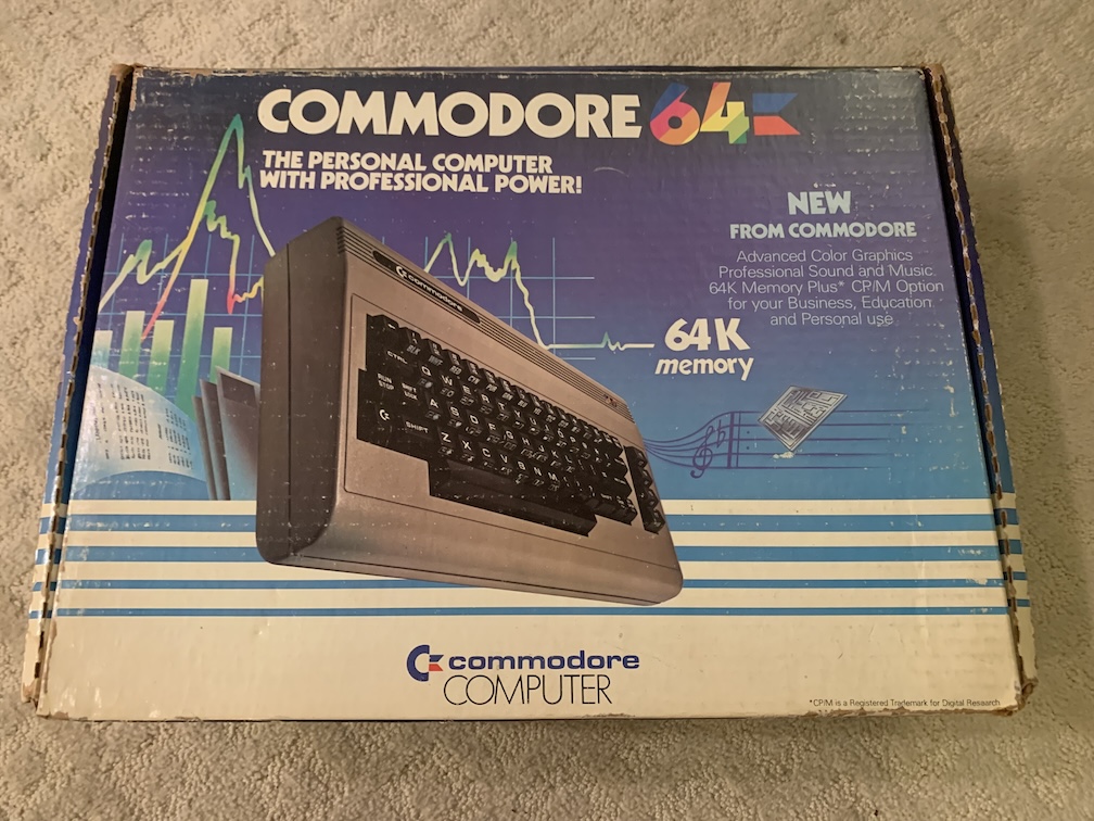 A somewhat degraded cardboard box featuring a color picture of a computer on the top, with colorful graphics showing a line and bar charts, and bold text on a blue background with the computer's model name and various features of the computer listed