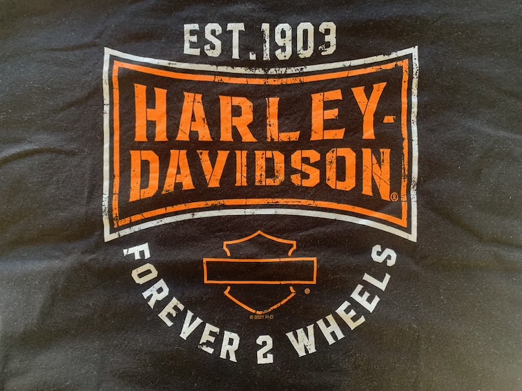 Front of a black T-shirt with a large Harley-Davidson logo and the words 'Forever 2 Wheels'