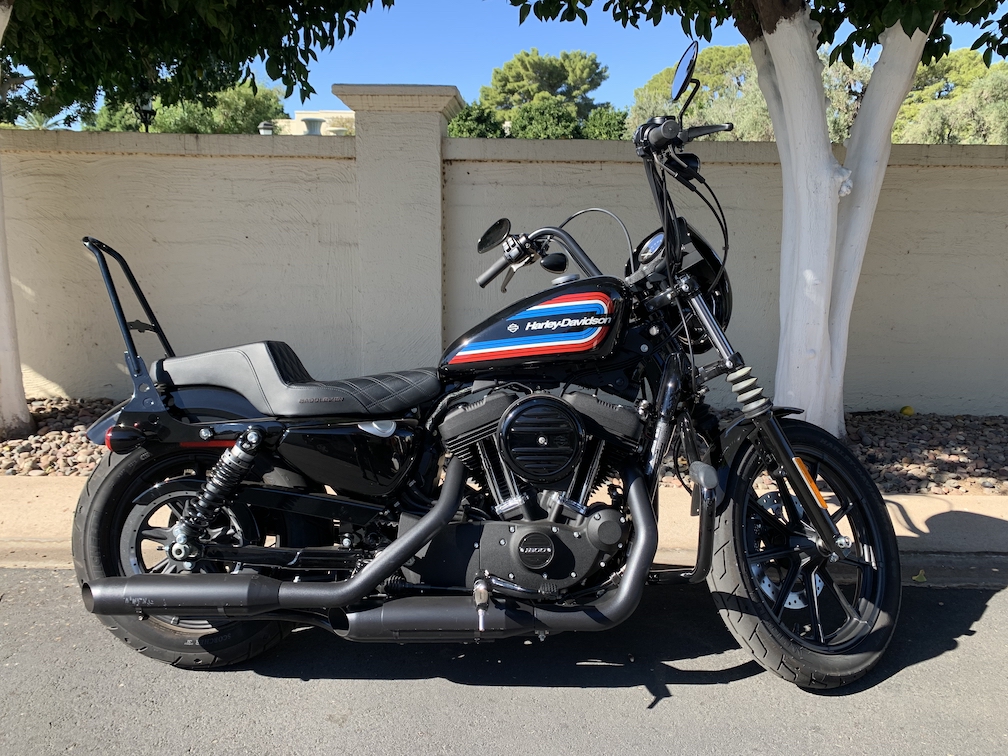 A black 2020 Harley-Davidson Sportster Iron 1200 cruiser motorcycle, viewed from the right side while parked on a sunny street
